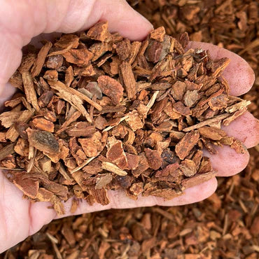 Hand holding a handful of brown wood chips or mulch.